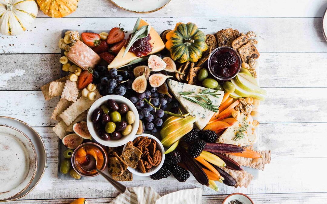 Zahngesunde Ernährung: Früchte und Speisen auf einem Brett auf einem weißen Holztisch.