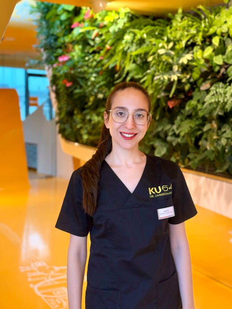 Zahnärztin Zeynep Çınar begrüßt Patienten bei KU64 in Berlin, Expertin für gesundes Zahnfleisch und Prophylaxe